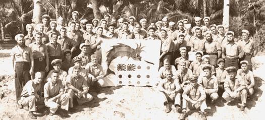 The crew of SS 393 with battleflag on the beach at Quam in 1944